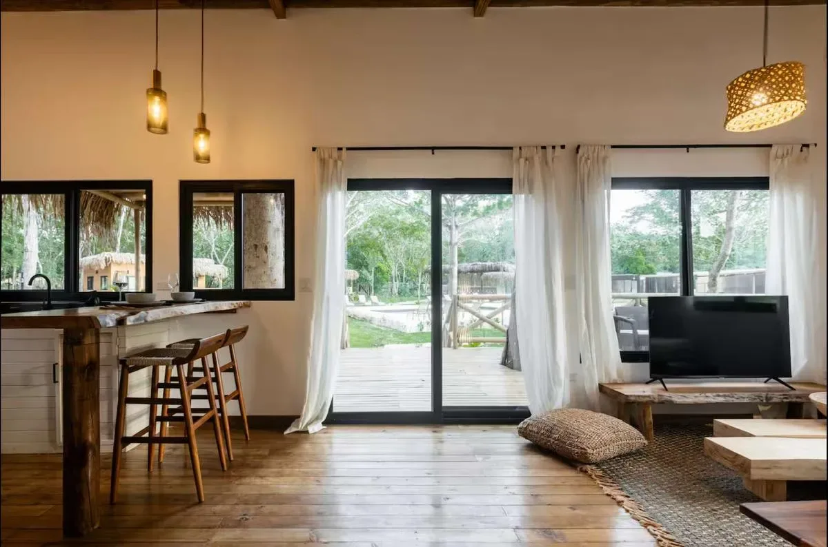 Una sala de estar con televisor, asientos y puertas de vidrio que dan a una terraza.