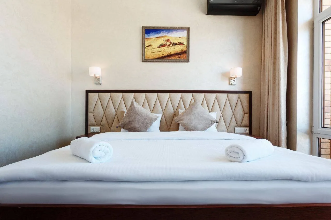 Espacio representativo del hotel: Un dormitorio con una cama bien tendida y un cuadro enmarcado sobre el cabecero.