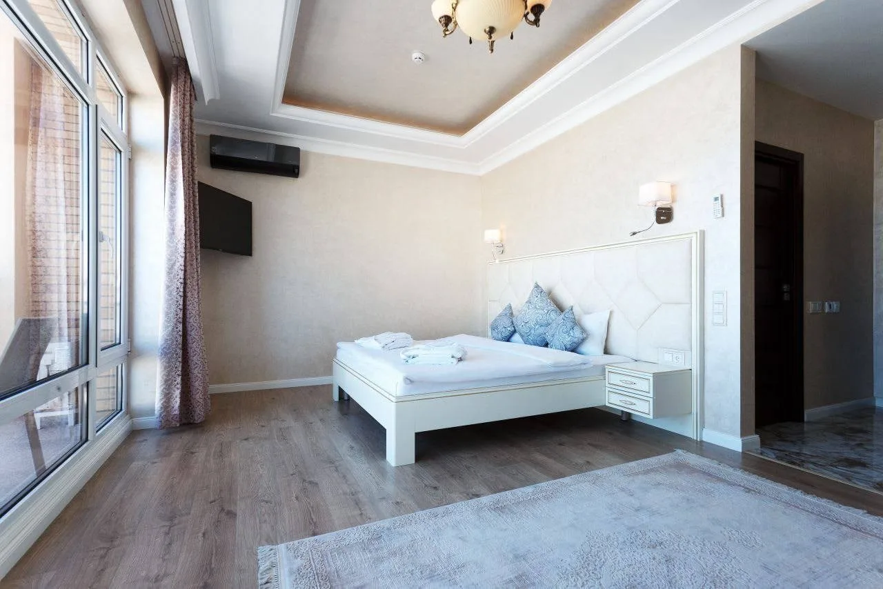 Espacio representativo del hotel: Un dormitorio luminoso con una cama blanca junto a grandes ventanas.