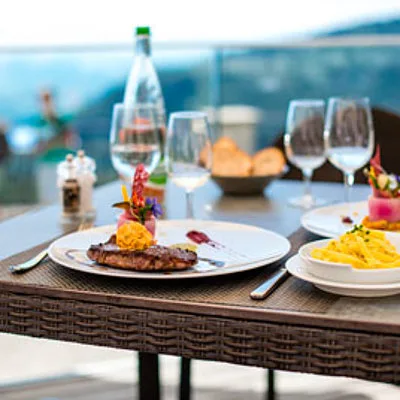 Representative hotel space: A dining table set with plated food and wine glasses overlooks the water.