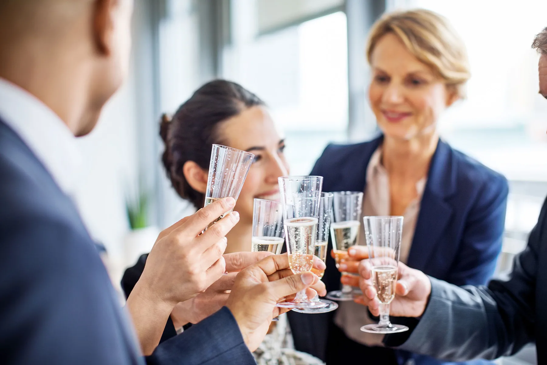 Representative hotel space: People gather for a toast with glasses in a bright indoor space.