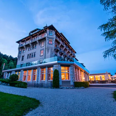 Representative hotel space: A multi-story hotel building stands beside a paved driveway at dusk.