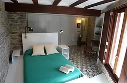 Espacio representativo del hotel: Un dormitorio con una cama, suelo de baldosas estampadas y vigas vistas en el techo.
