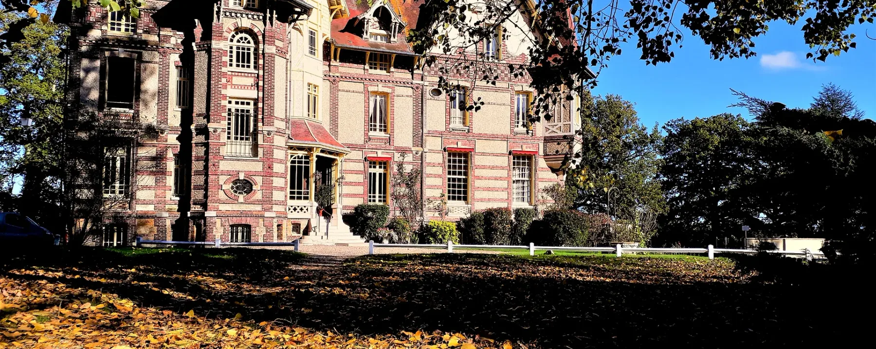 Representative hotel space: A large historic-looking building stands behind a tree-lined lawn.