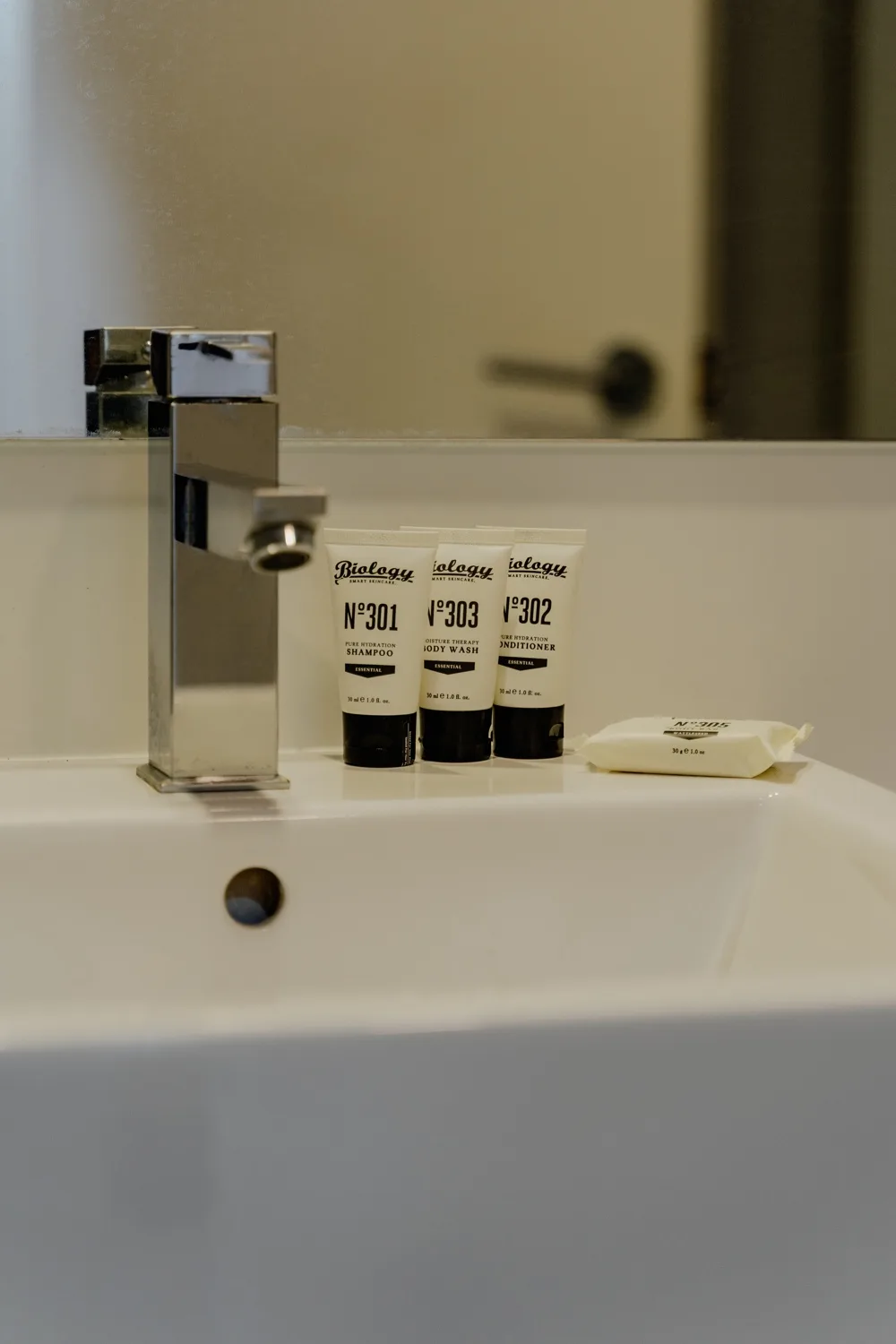 A bathroom sink with a metal faucet and toiletries on the counter.