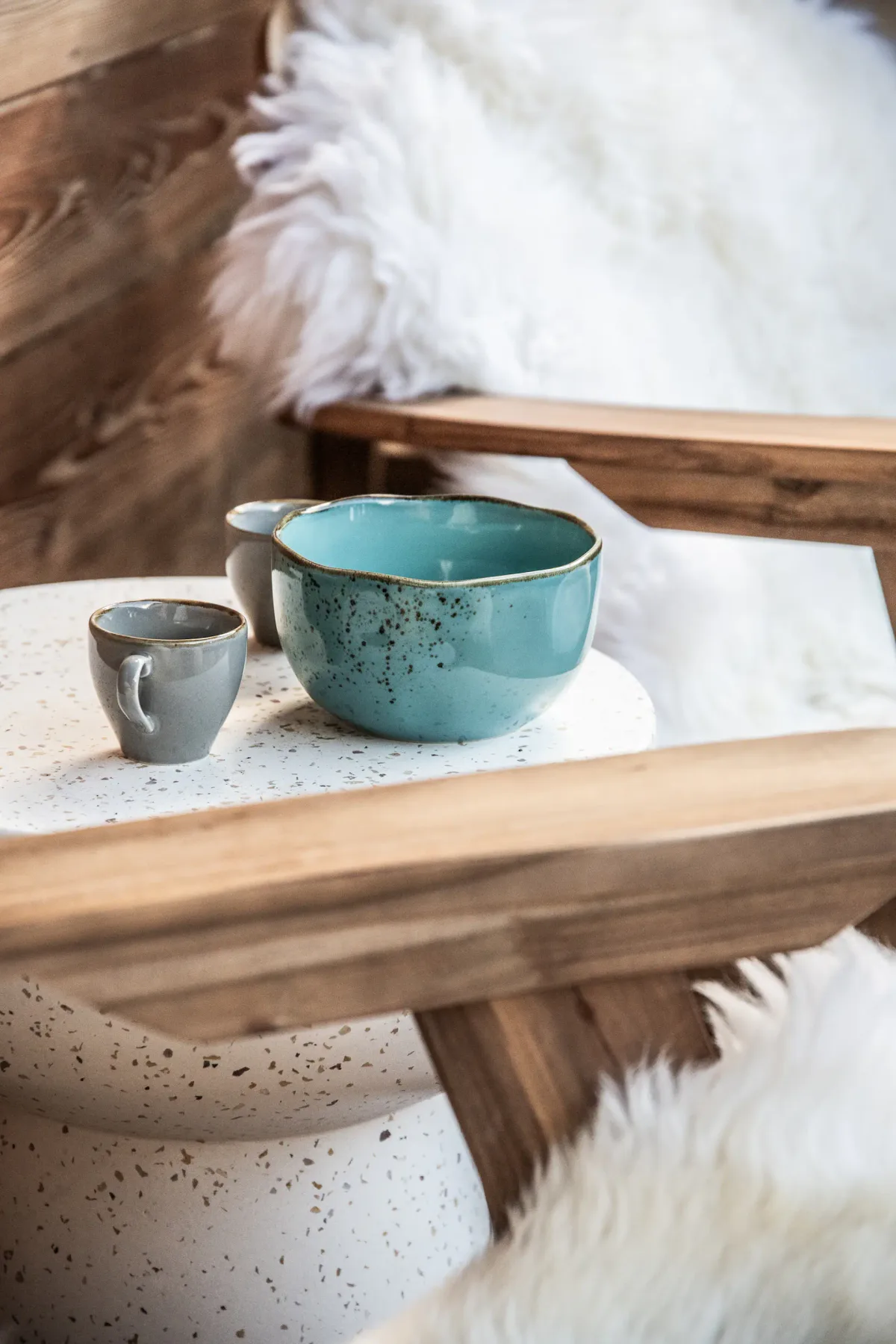 A small table holds ceramic cups beside a white fluffy rug.