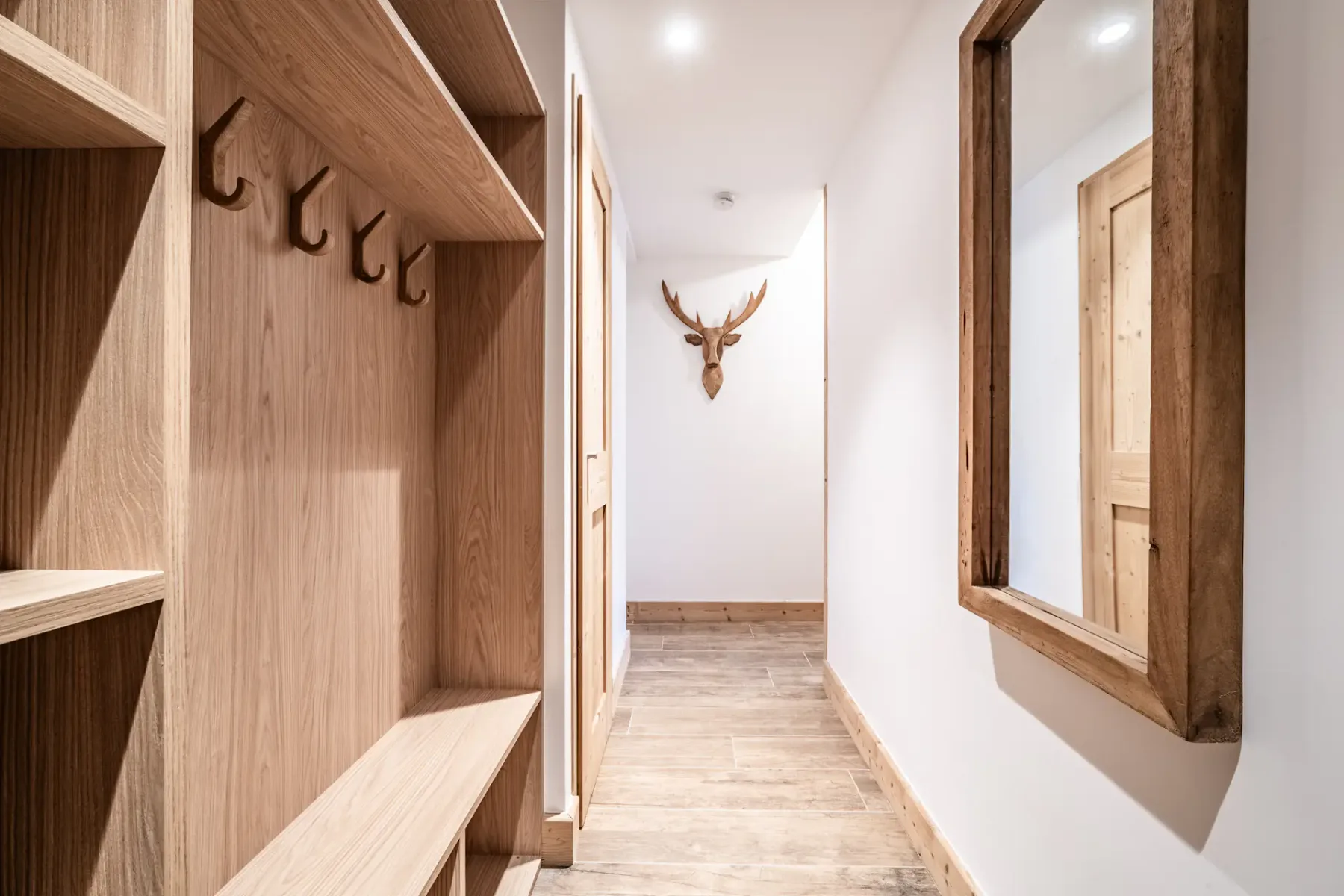 A bright hallway with built-in wooden shelving and a mounted deer head.