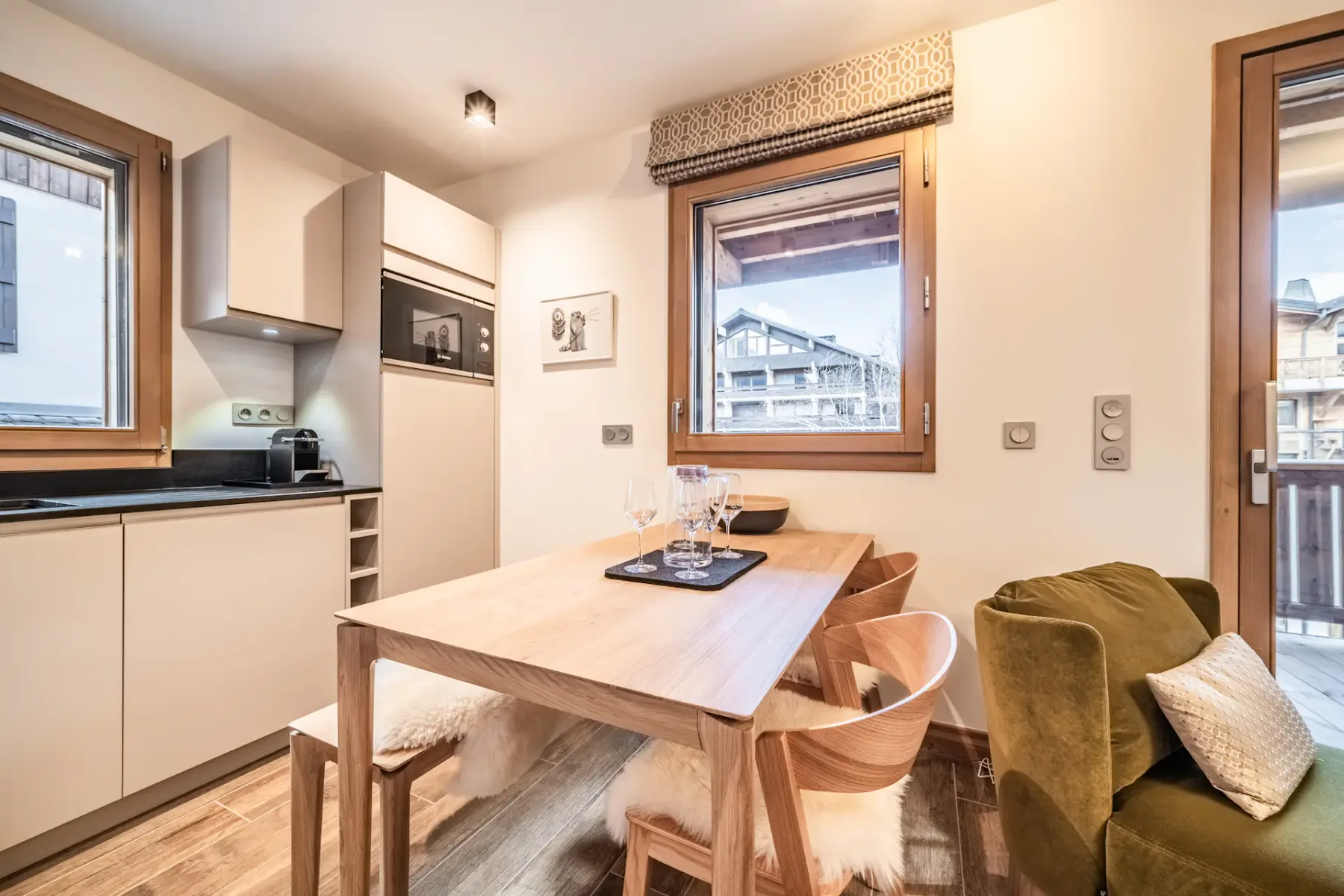 A compact kitchen and dining area with a wooden table beside several windows.