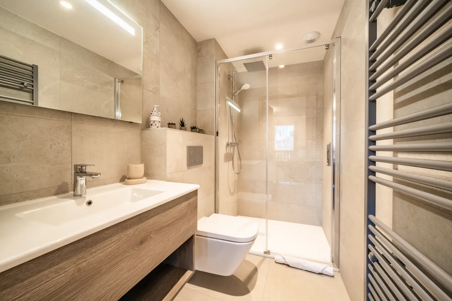 A bright bathroom with a long vanity and a glass shower.