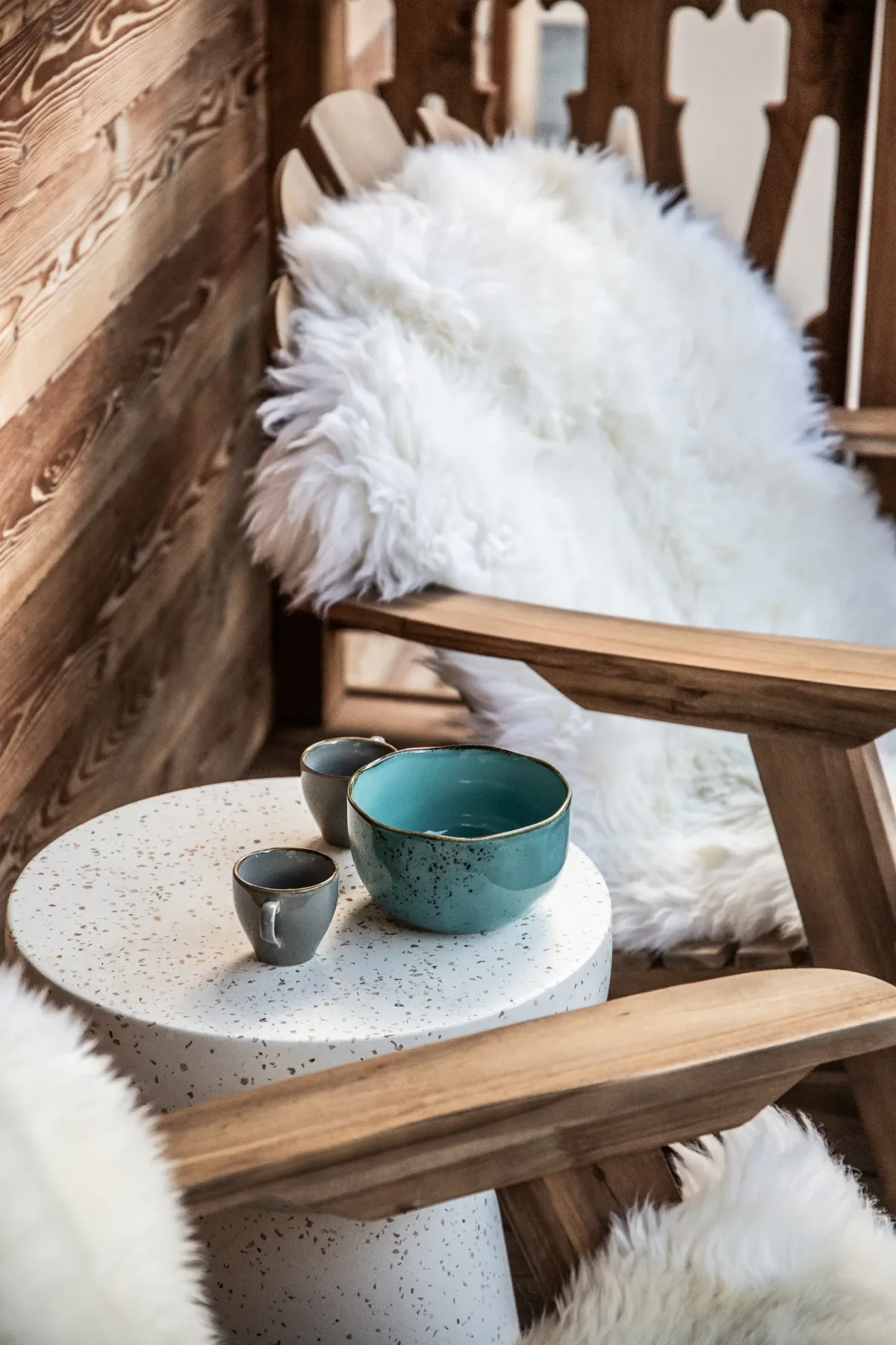 A rustic seating area with a small round table and fluffy white throws.