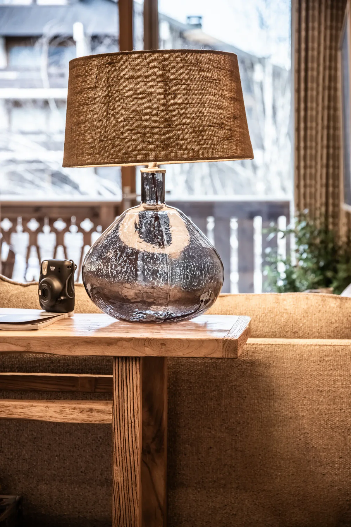 A table lamp sits on a wooden side table beside upholstered seating.