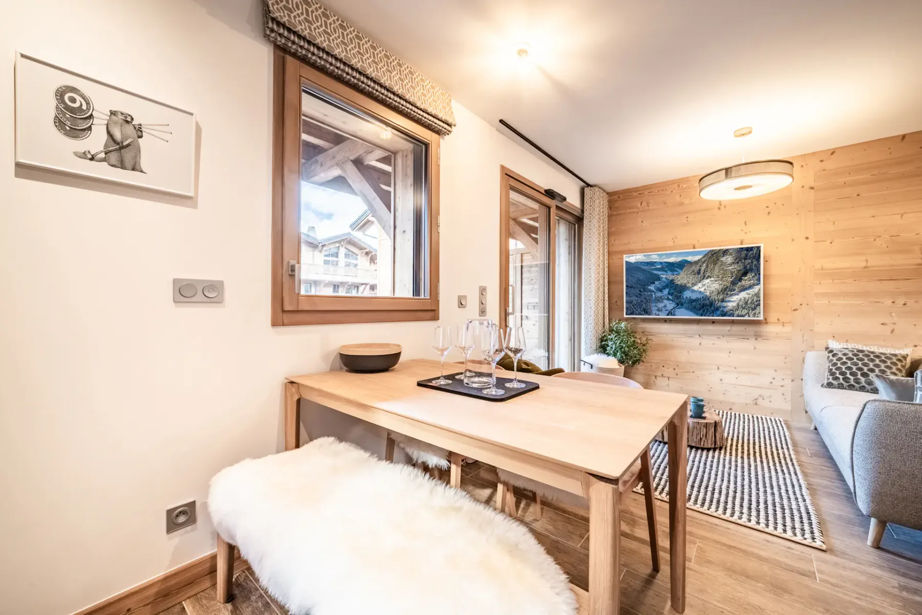 A dining area with a wooden table beside a bright living space.