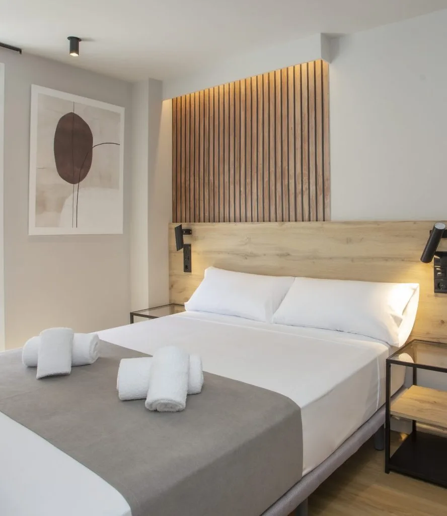 Espacio representativo del hotel: Un dormitorio con una cama bien tendida y una obra abstracta en la pared.