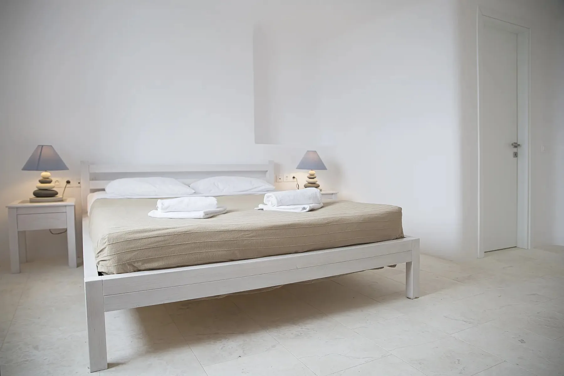 A bedroom with a white bed, neatly made with light-colored bedding.
