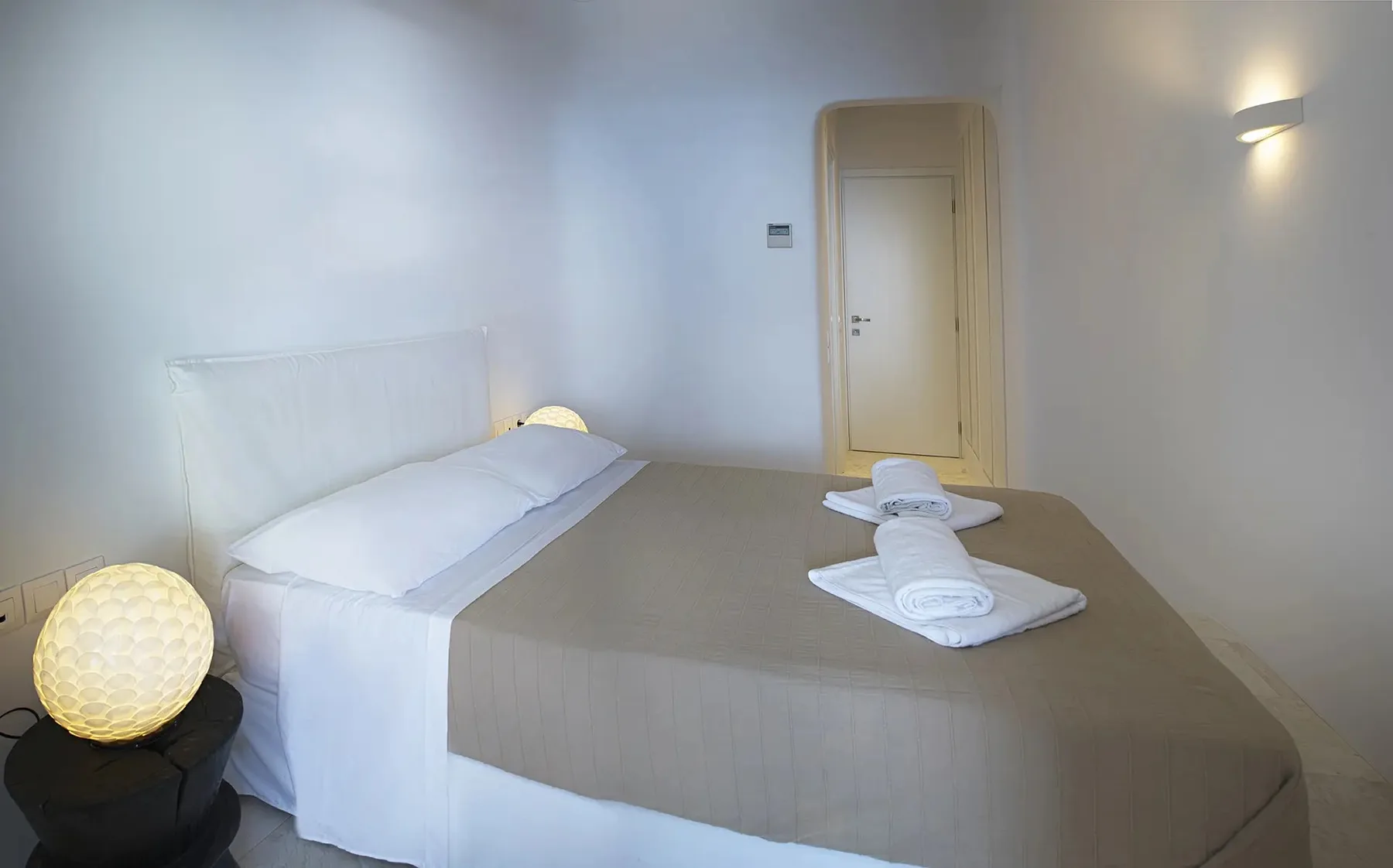 A bedroom with a neatly made bed and folded towels.