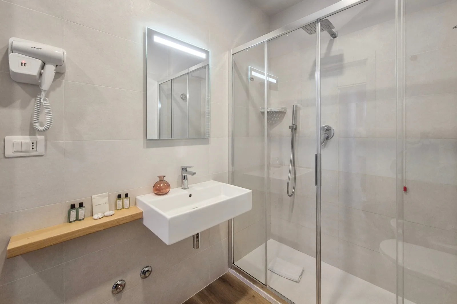 Representative hotel space: A tiled bathroom with a sink and glass shower.