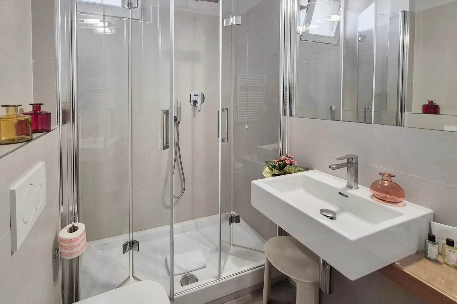 Representative hotel space: A bright bathroom with a glass-enclosed shower and a wall-mounted sink.