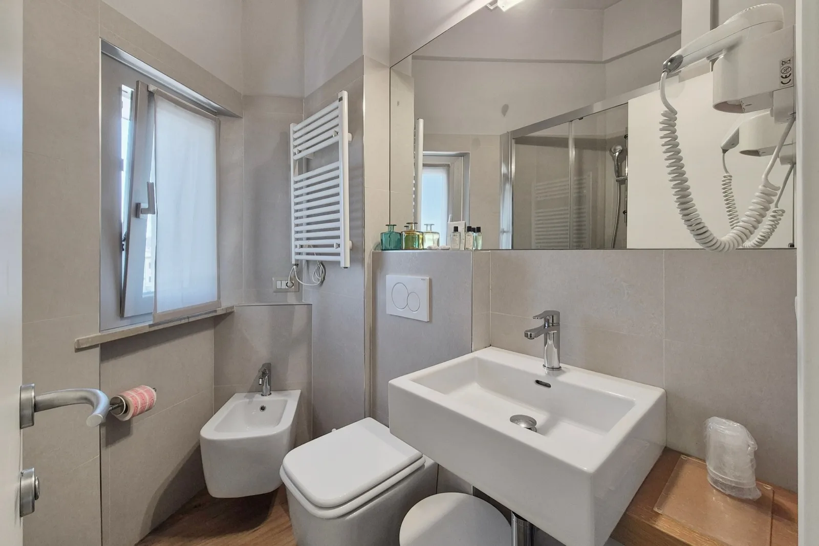 Representative hotel space: A tiled bathroom with a sink, toilet, and wall-mounted shower.