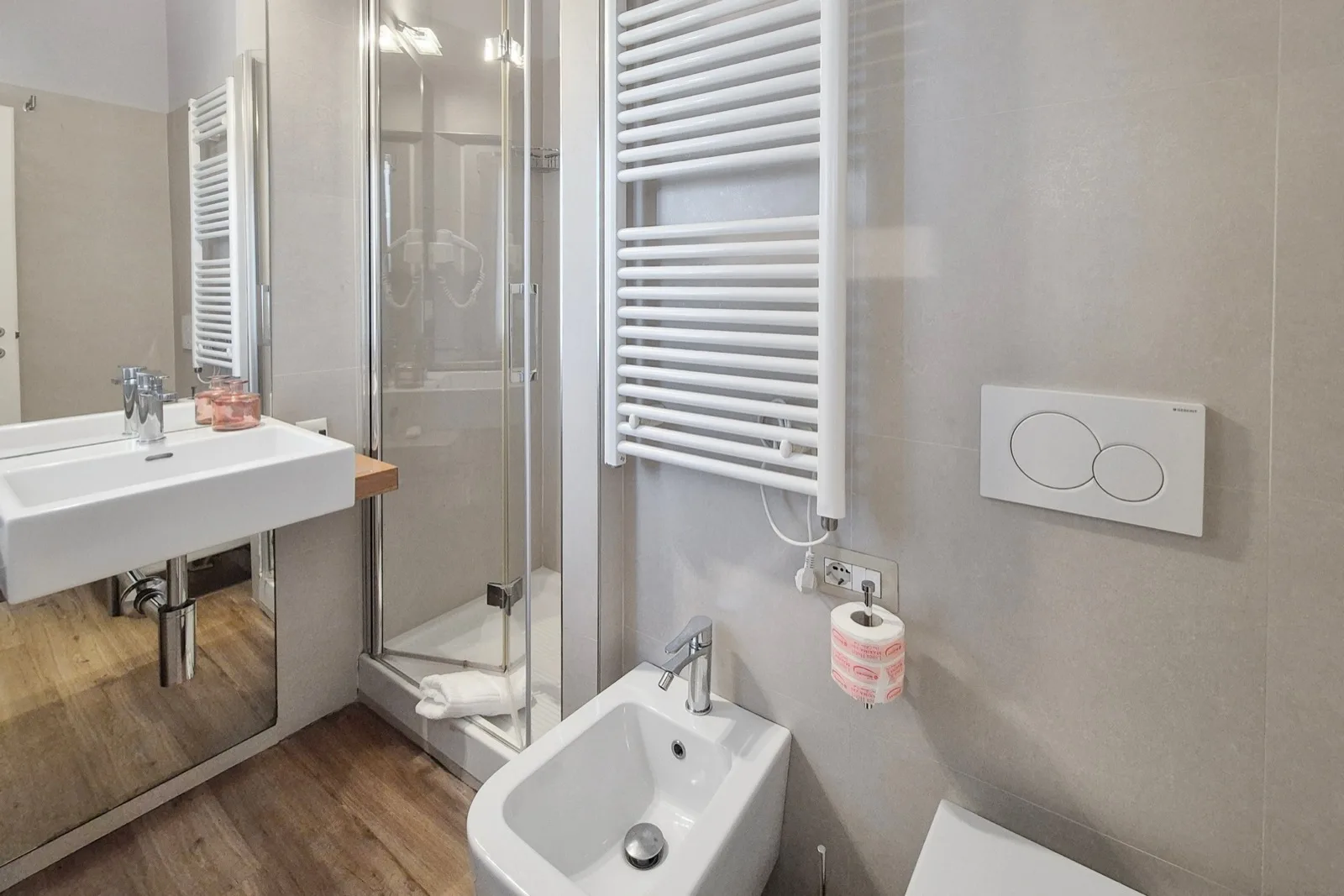 Representative hotel space: A bathroom with a glass shower, sink, and wall-mounted towel warmer.
