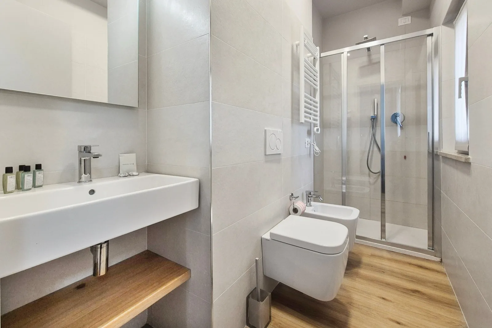 Representative hotel space: A modern bathroom with a wall-mounted sink and glass shower.