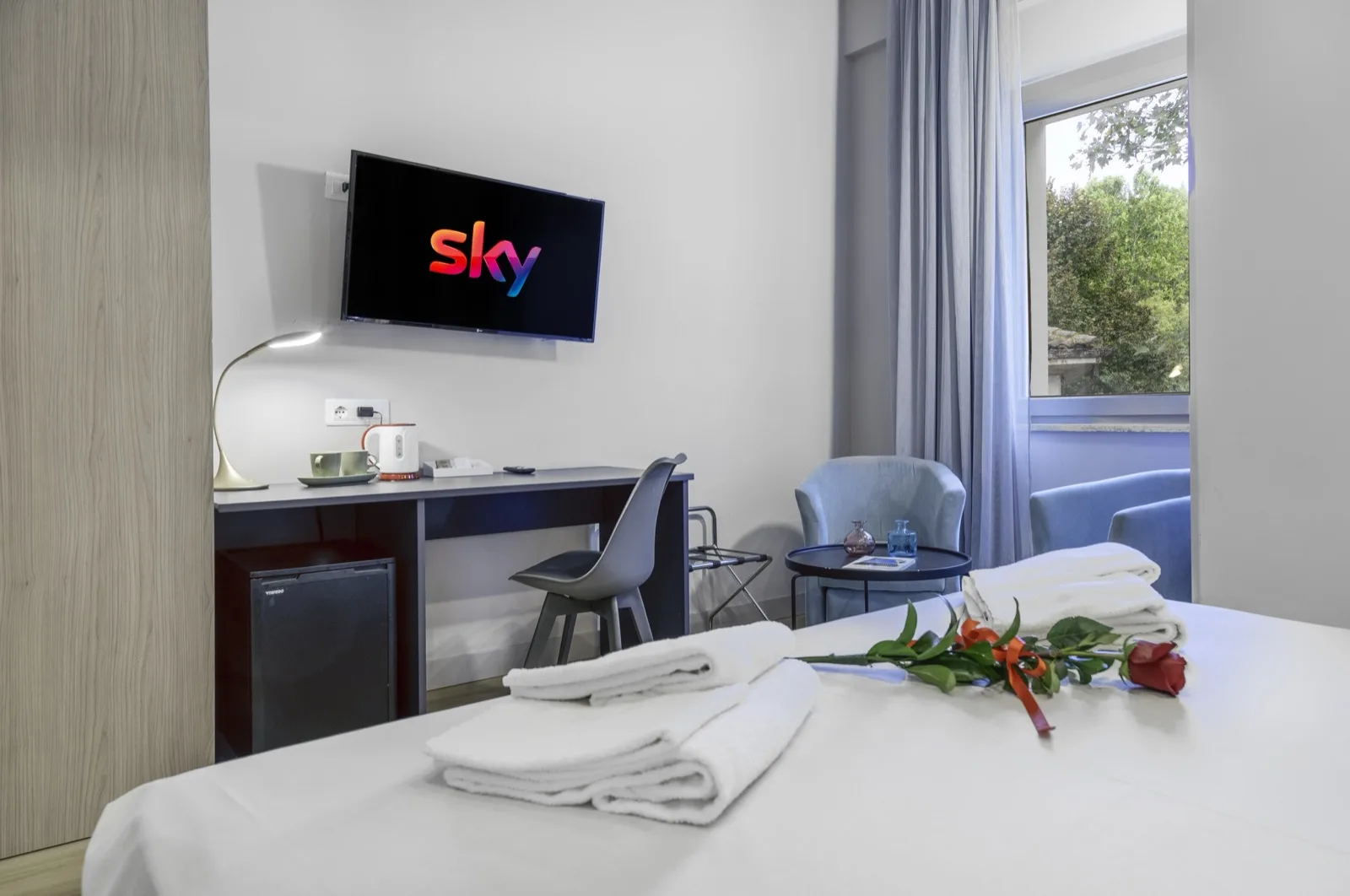 Representative hotel space: A hotel room with a desk, seating, and a bed arranged in the foreground.