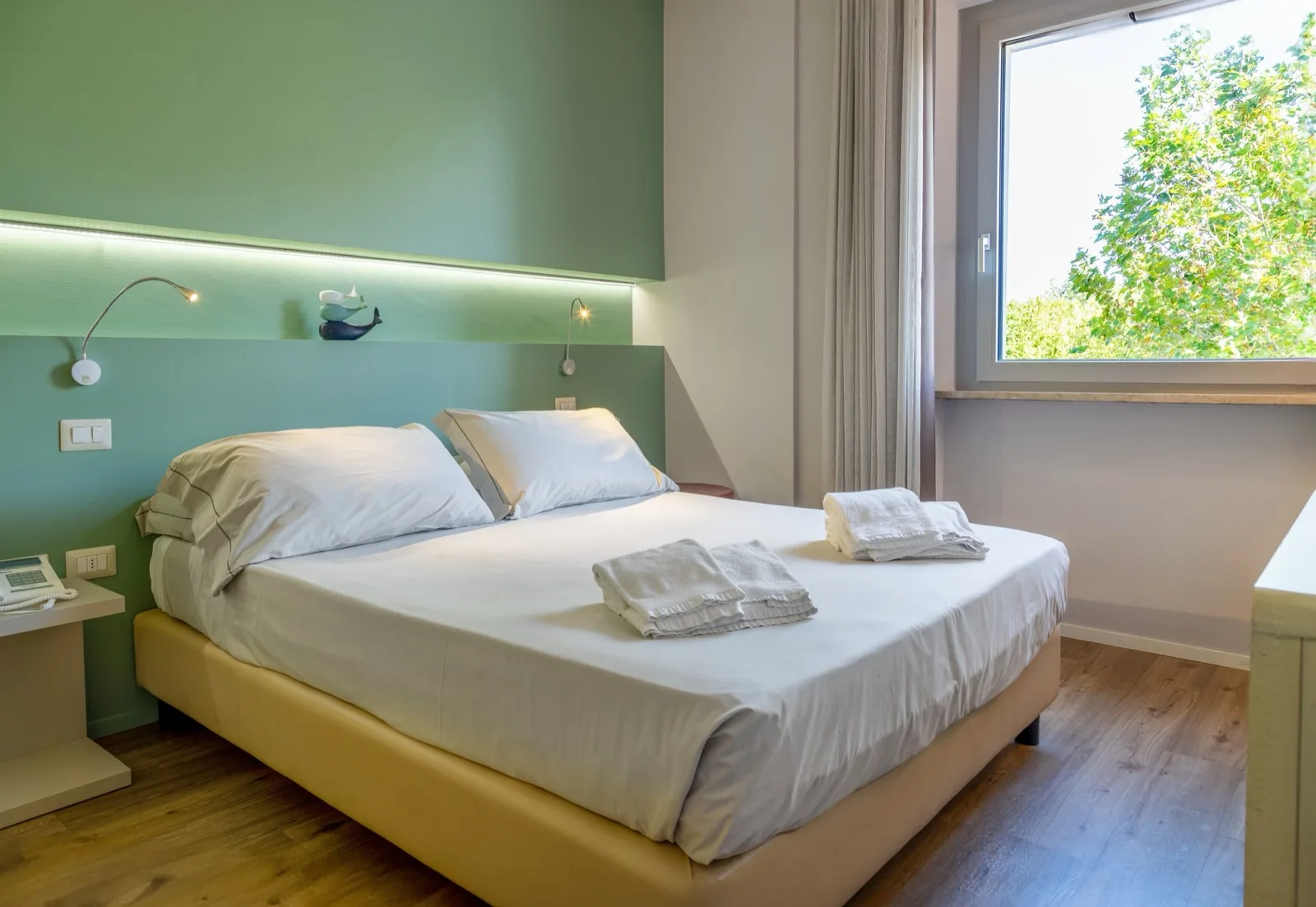 Representative hotel space: A bedroom with a neatly made bed and a large window.