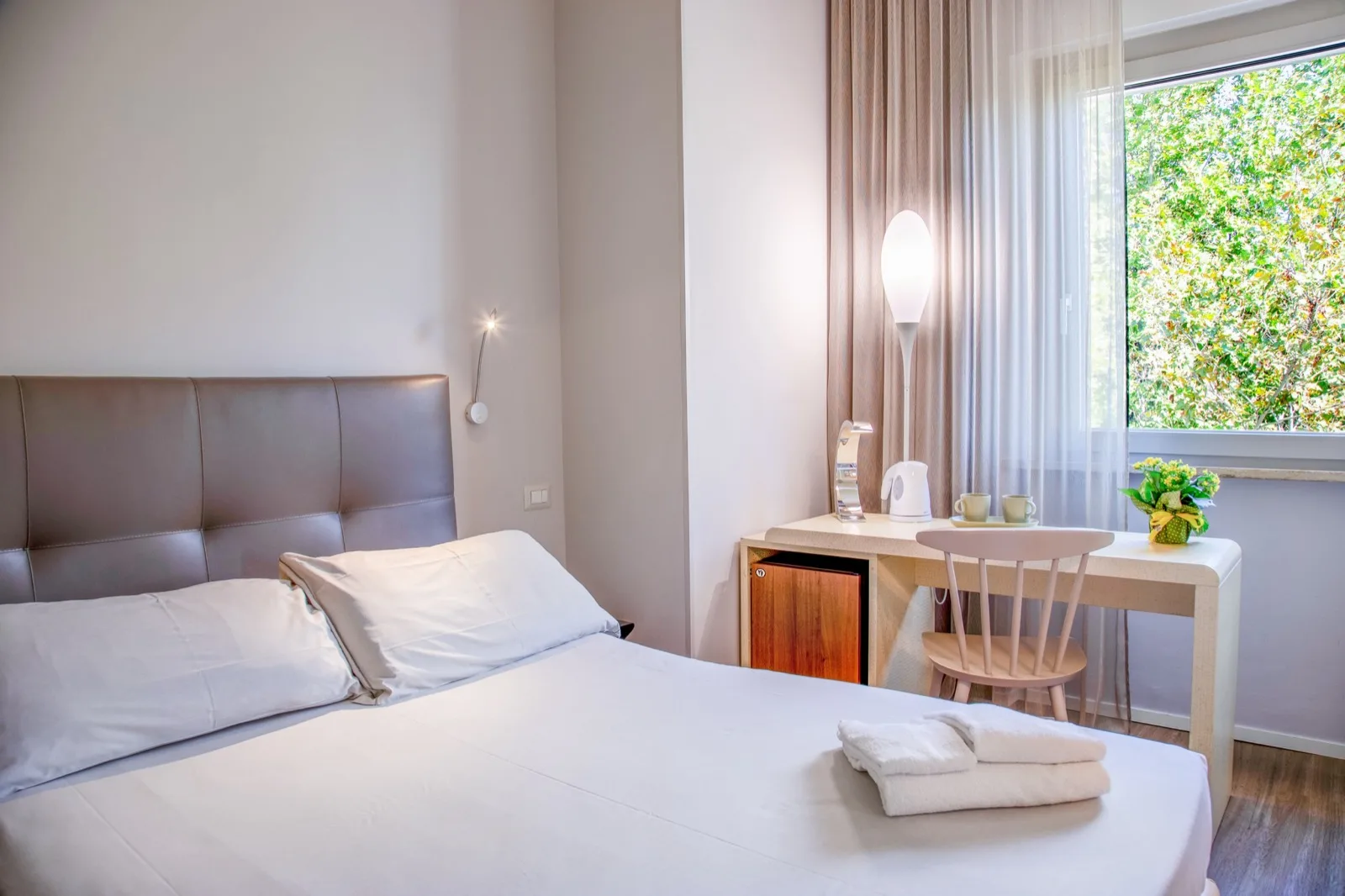 Representative hotel space: A bedroom with a bed beside a desk and a large window.