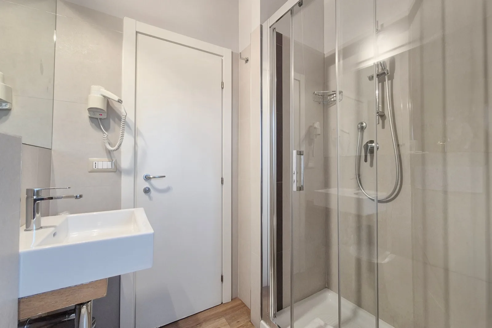 Representative hotel space: A bathroom with a wall-mounted sink and glass shower.