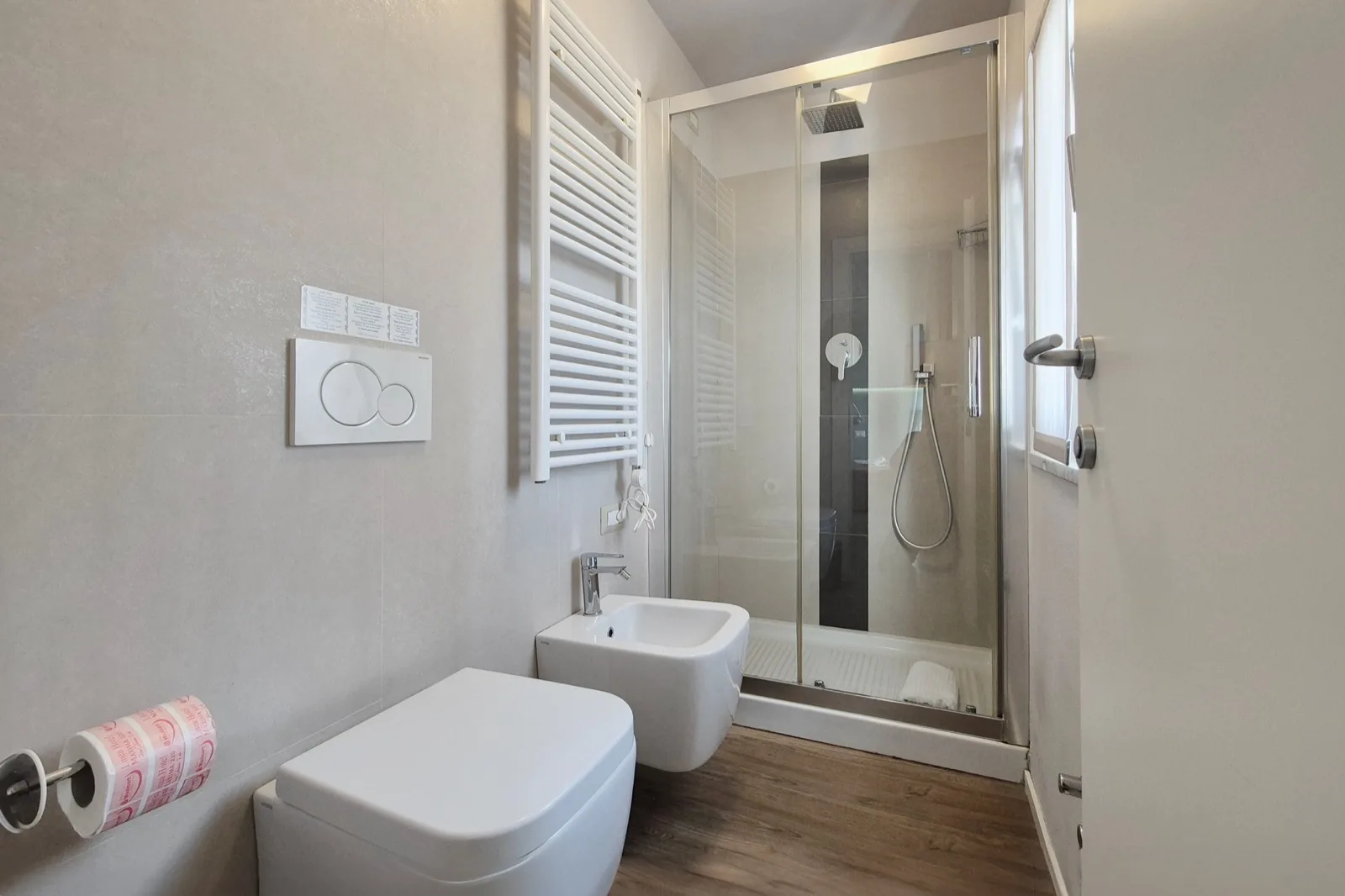 Representative hotel space: A modern bathroom with a toilet, sink, and glass shower.