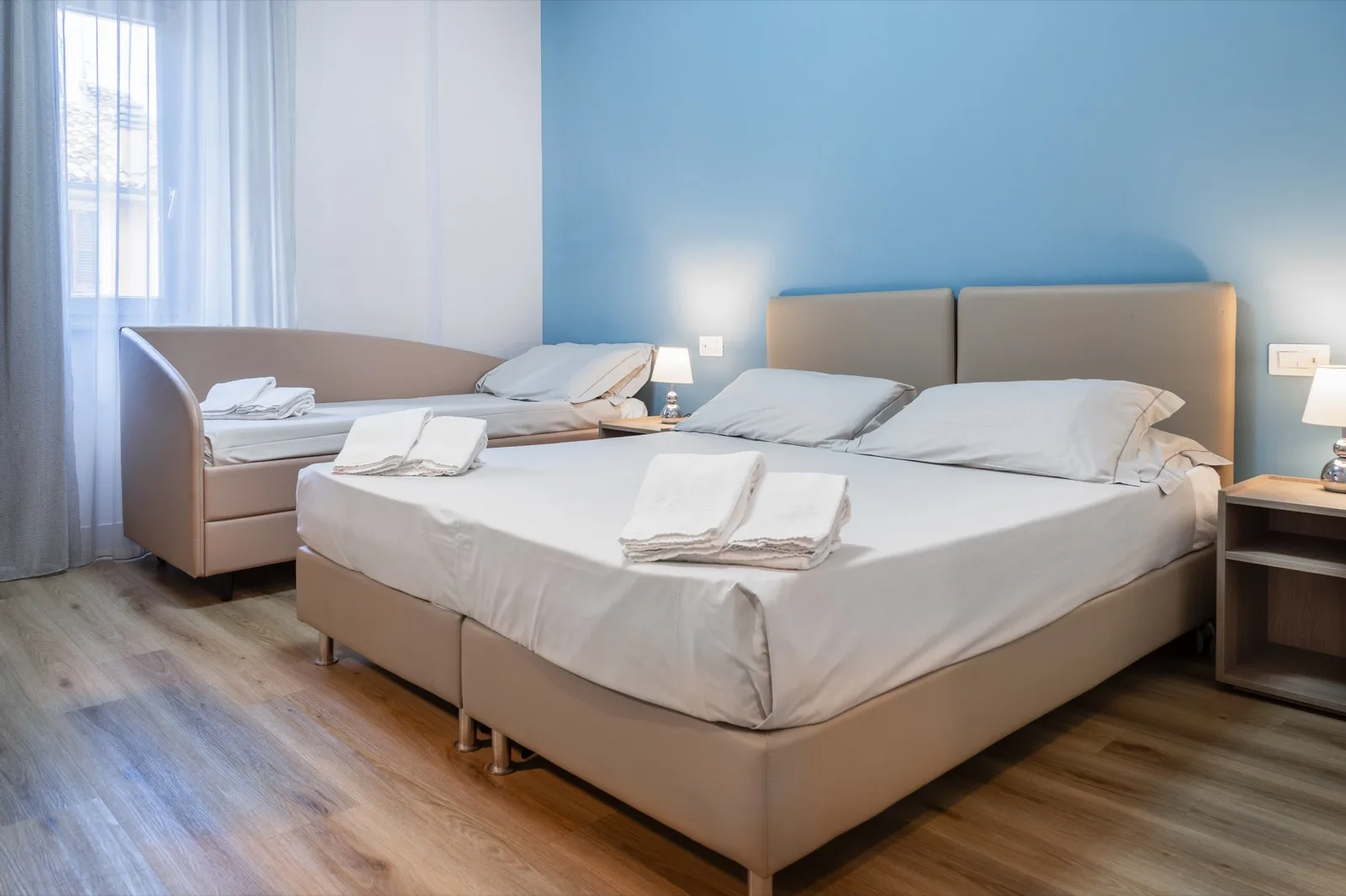 Representative hotel space: A bedroom with a large bed and a smaller bed beside the window.