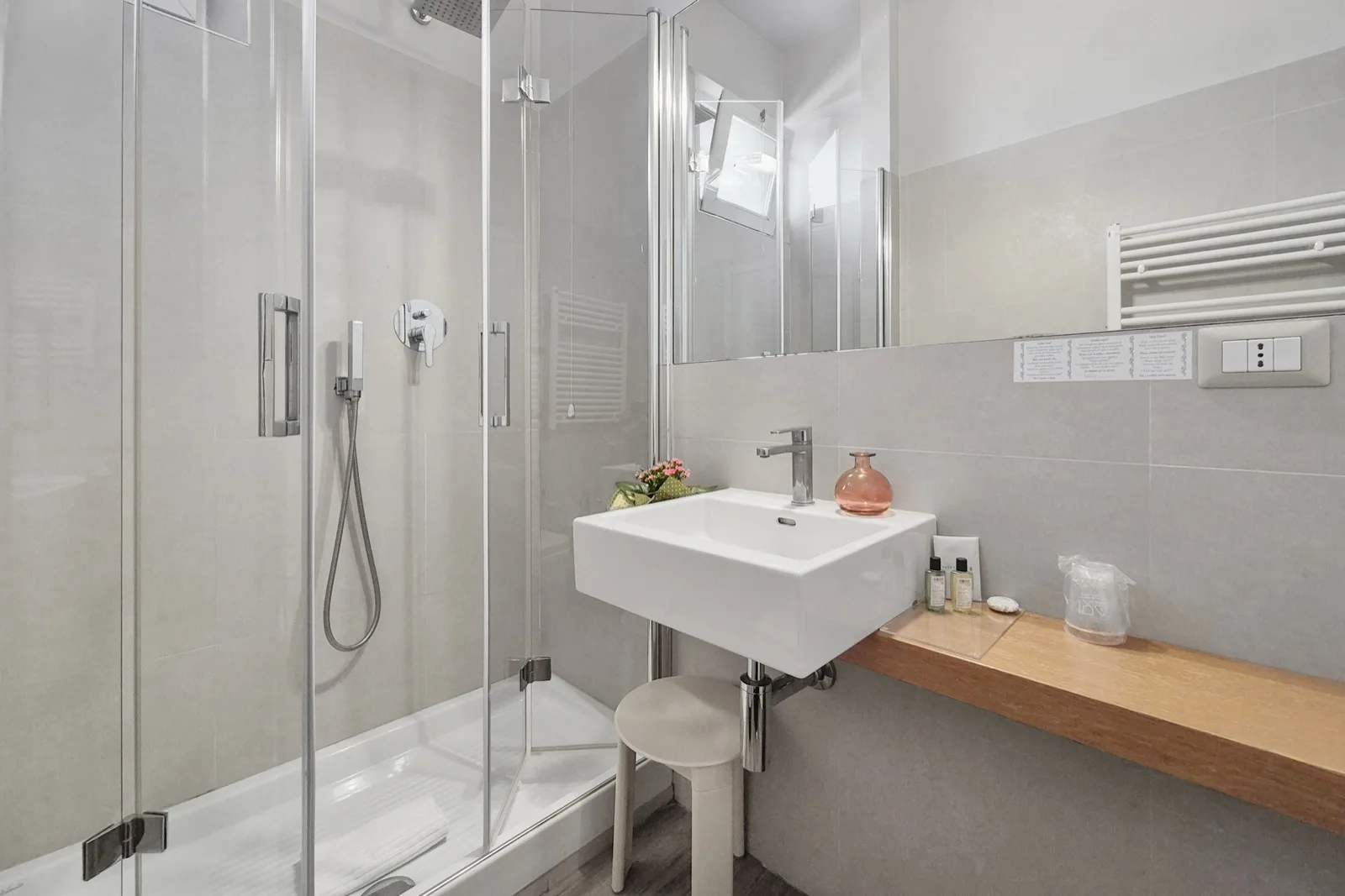 Representative hotel space: A bright bathroom with a glass shower and a wall-mounted sink.