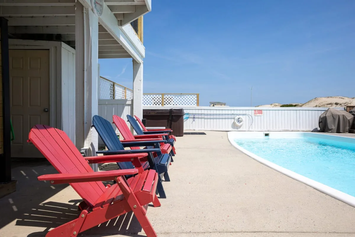 A poolside patio with colorful lounge chairs beside the water.
