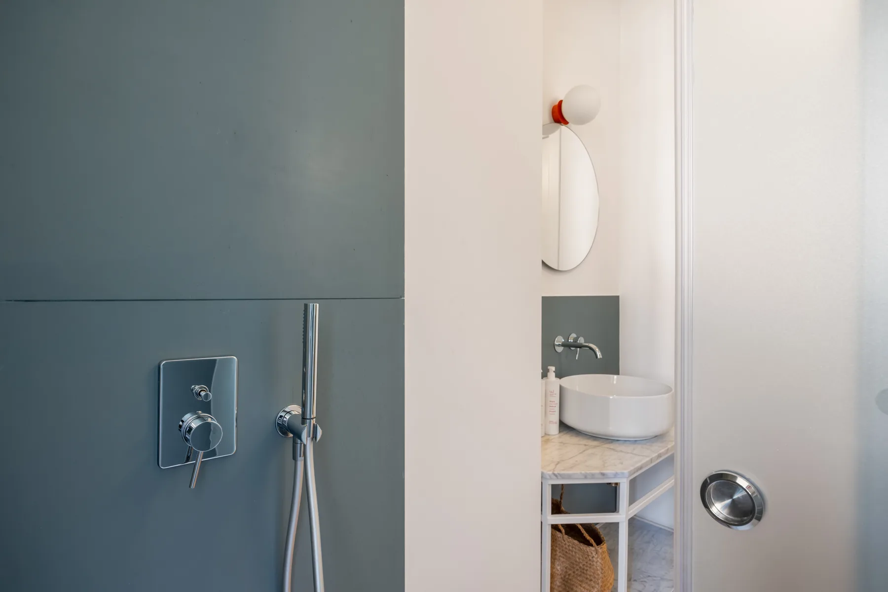 A modern bathroom with a wall-mounted shower and a vessel sink.