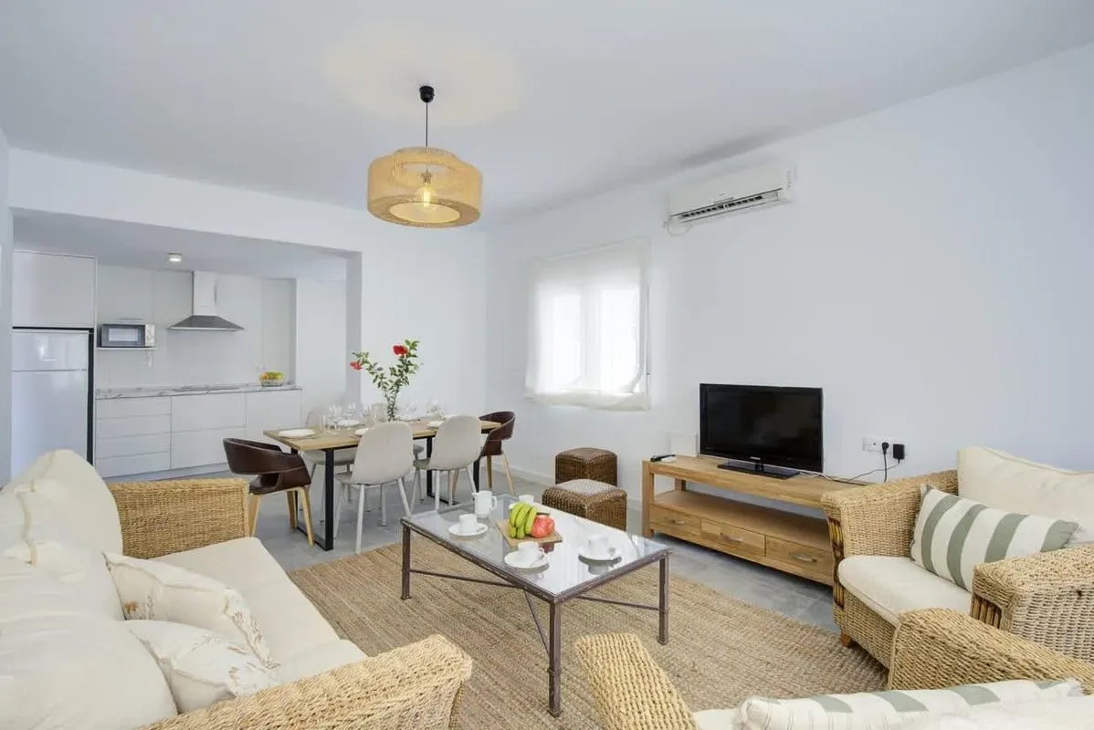 A bright living room with seating, a television, and an adjoining dining area.