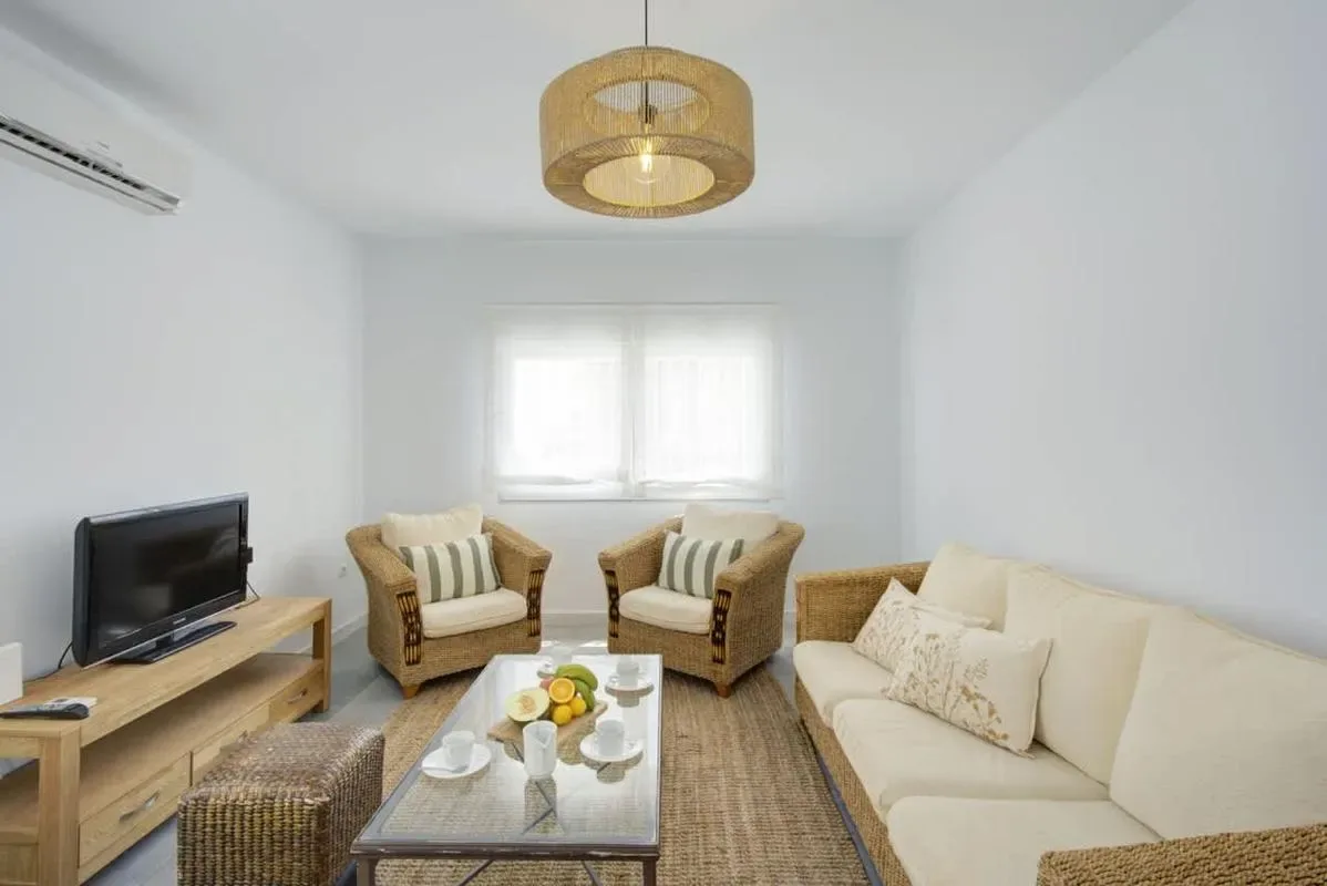 A bright living room with seating arranged around a coffee table and television.