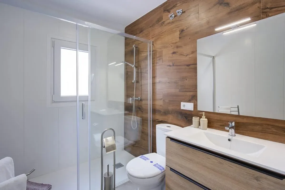 A bathroom with a glass shower, toilet, and vanity.