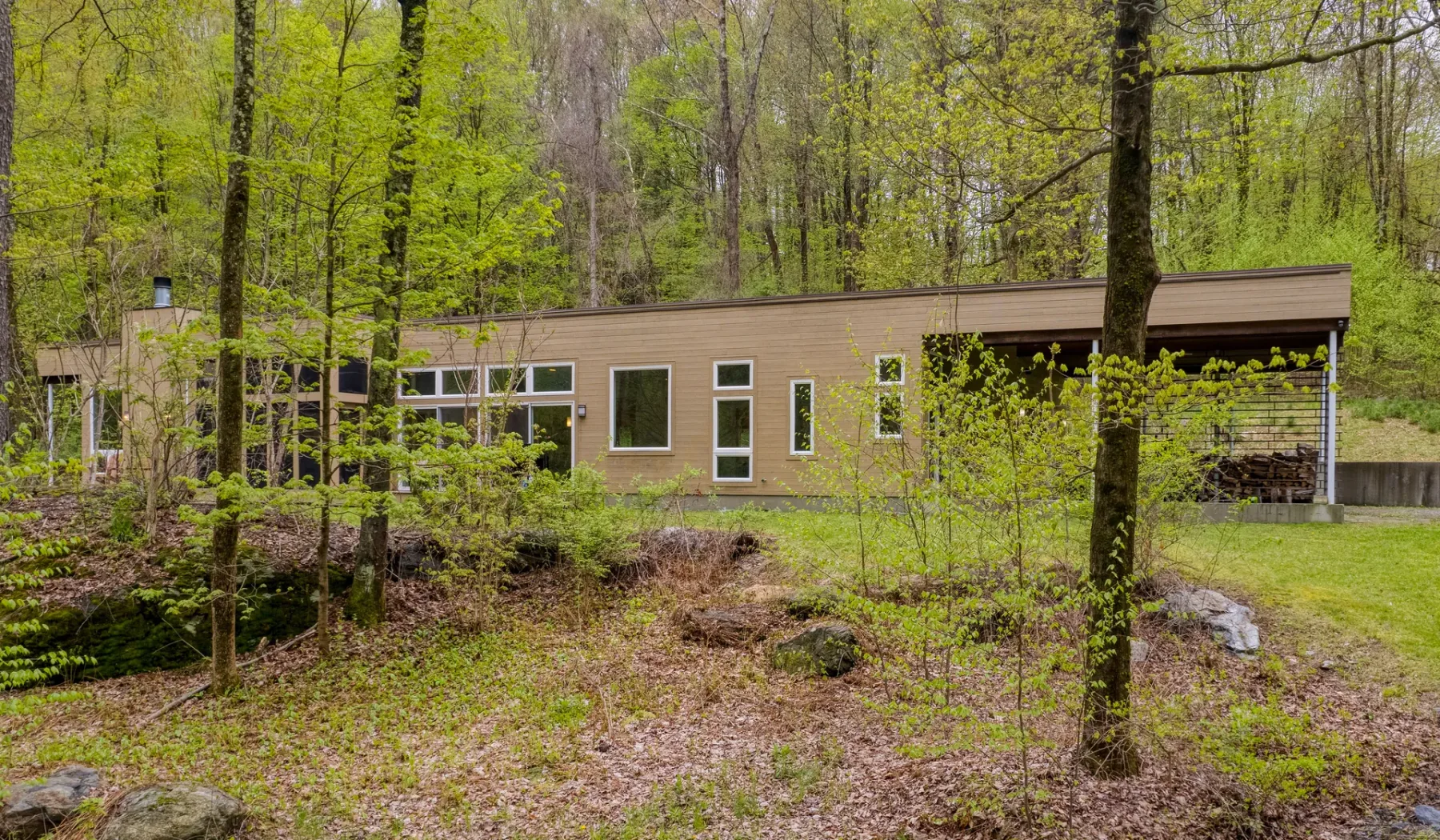 A low modern building with several windows sits among leafy trees.