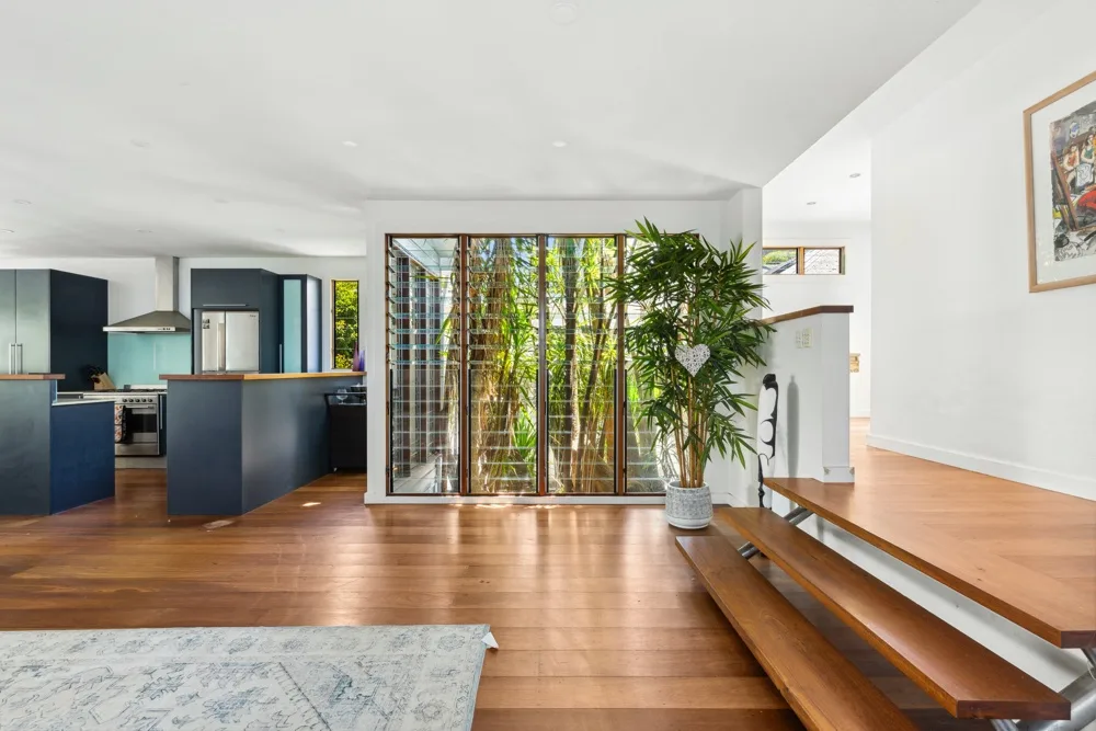 Una cocina y comedor de planta abierta, con suelo de madera y una gran abertura acristalada.