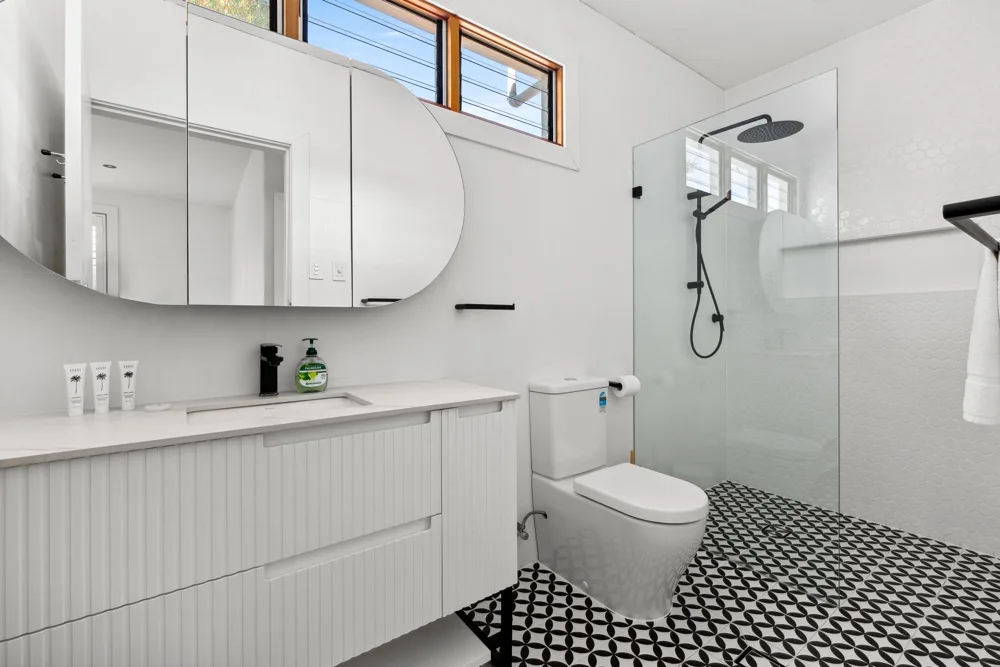 Un baño luminoso con lavabo, inodoro y ducha de vidrio.