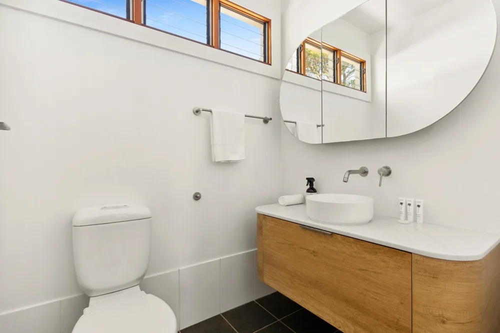 Un baño luminoso con lavabo, inodoro y un gran espejo de pared.