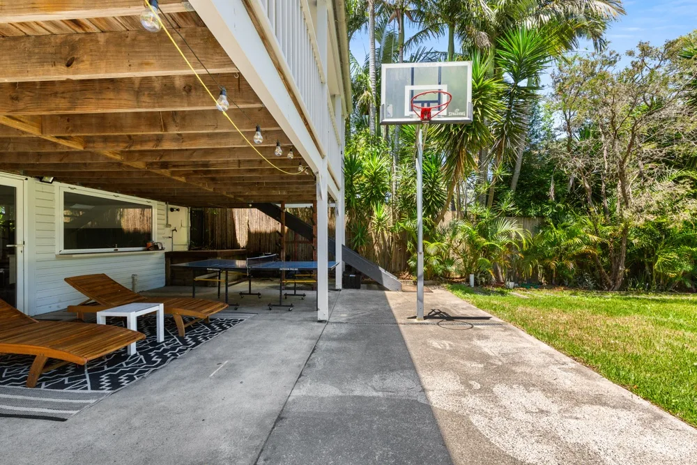 Una canasta de baloncesto está junto a un patio cubierto y un jardín.