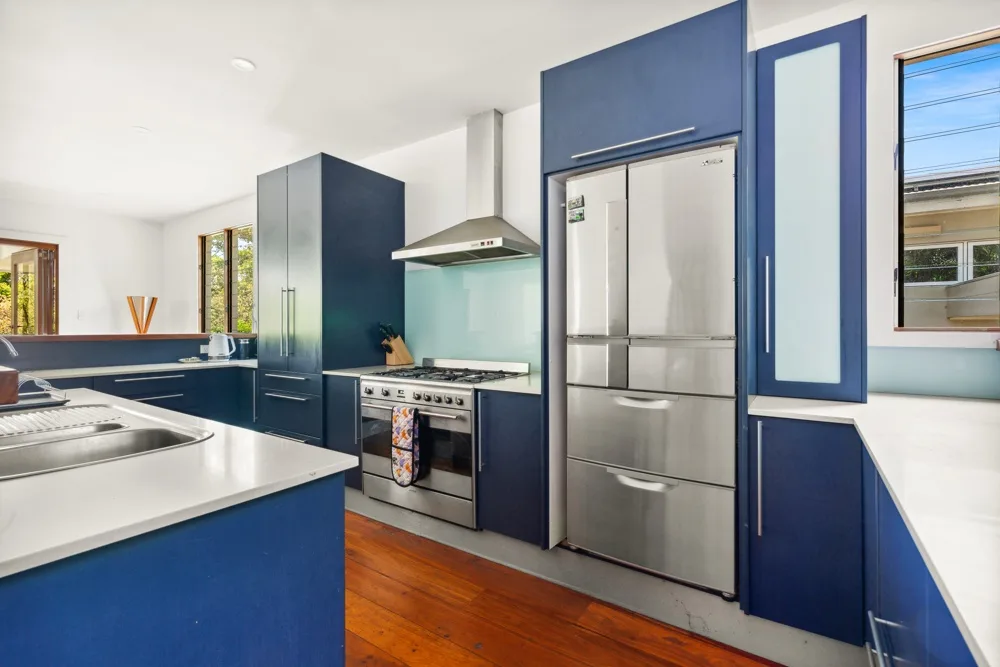 Una cocina moderna con gabinetes azules, electrodomésticos de acero inoxidable y una encimera blanca.