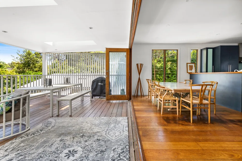 Un comedor abierto con una mesa de madera junto a una terraza cubierta.