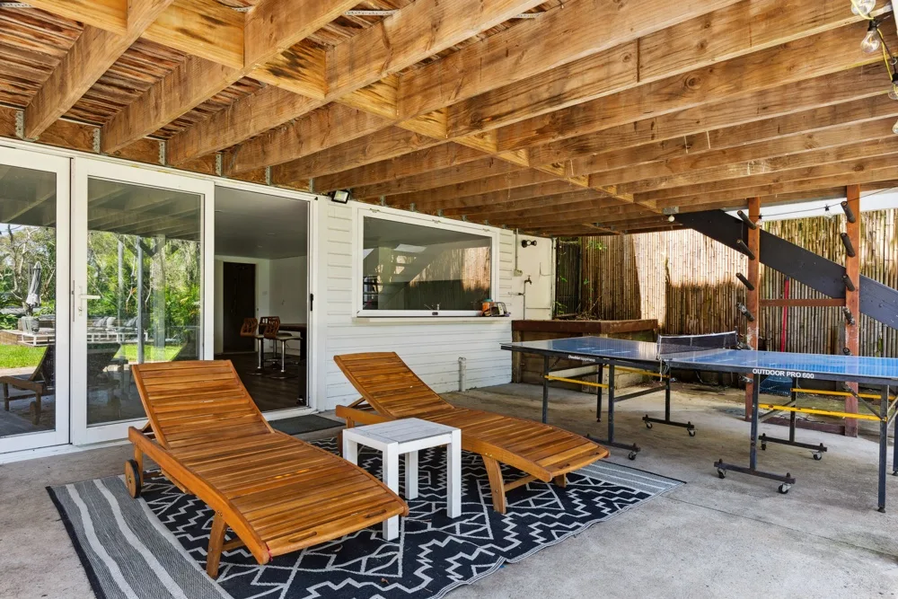 Un patio exterior cubierto con asientos de madera y una mesa larga.