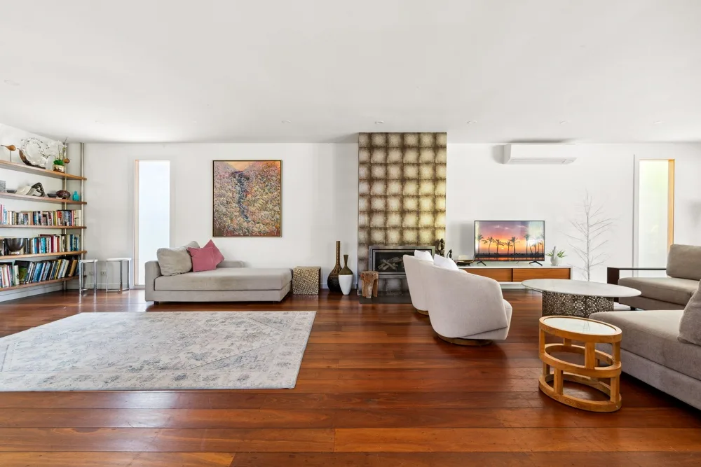Una sala de estar amplia con asientos, una alfombra grande y un televisor.