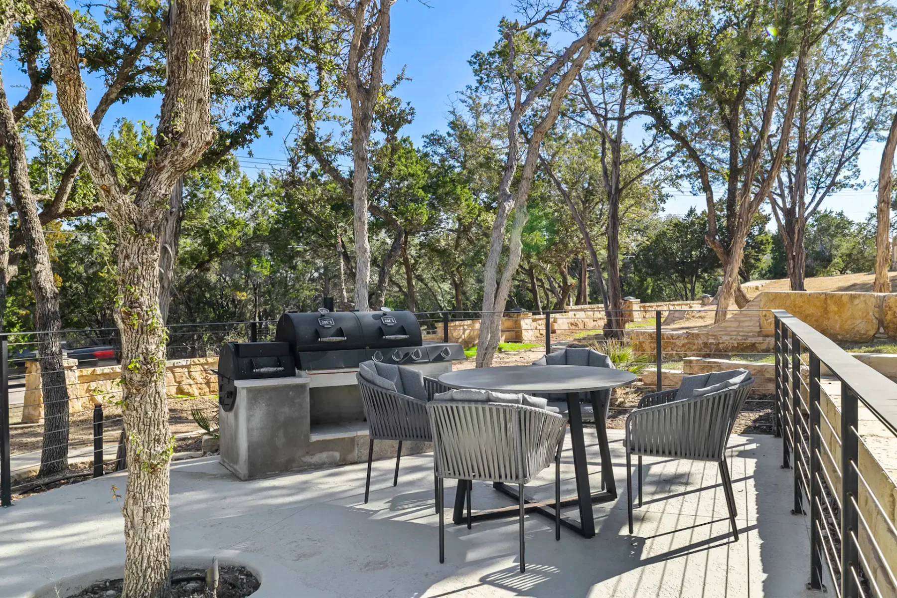 Shared amenity: Outdoor patio with a dining table and seating among trees.