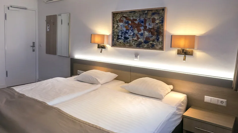 Representative hotel space: A bedroom with two beds beneath a large abstract painting.