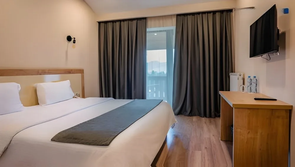 Representative hotel space: A hotel bedroom with a bed, dark curtains, and a wooden desk.