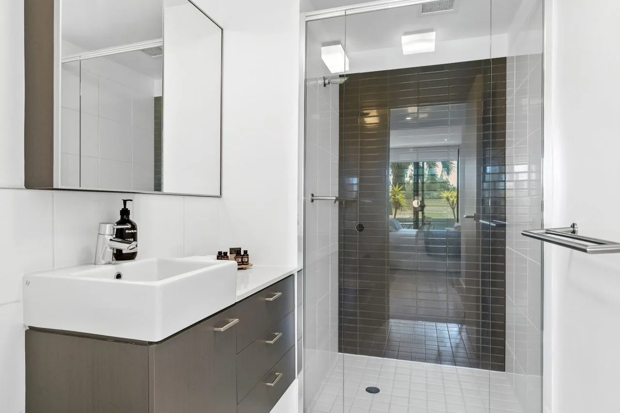 Un baño moderno con un lavabo junto a una ducha con mampara de vidrio.