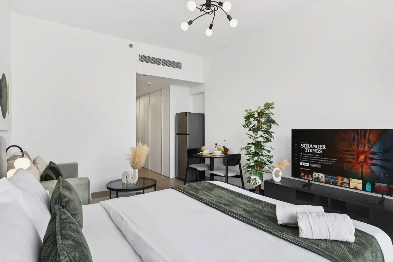 Un dormitorio con cama, zona de estar, televisor y planta en maceta.